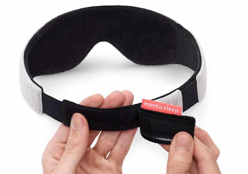 Hands demonstrating the micro hook and loop closure of a sleep mask.