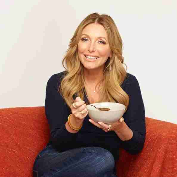 Dr. Kellyann Petrucci sitting on red couch with a bowl and spoon