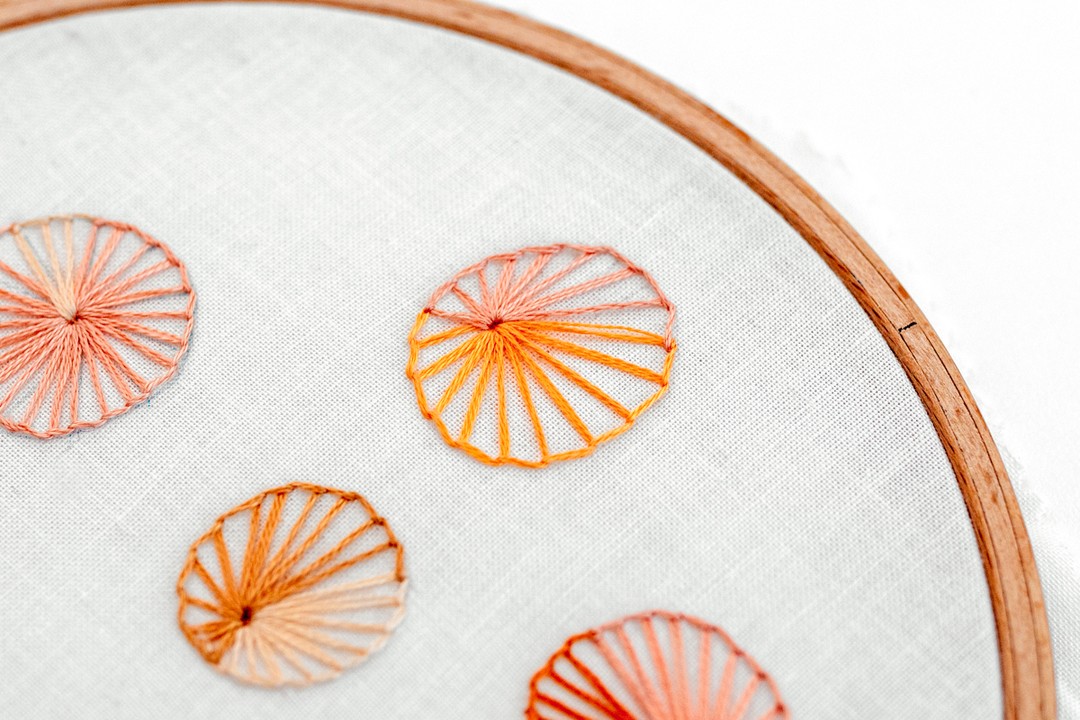 Multiple buttonhole wheel shapes have been created on embroidery fabric.