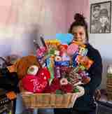 A woman holds basket filled with candy, plush toys, and roses