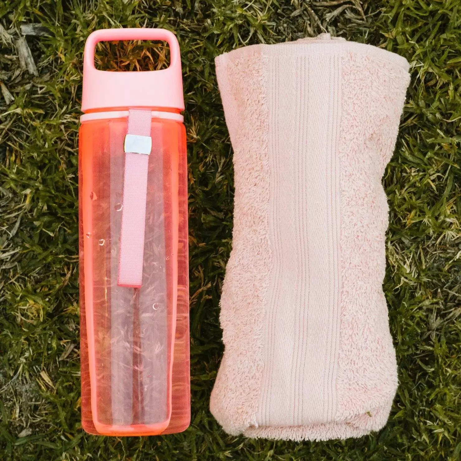 “Bouteille d’eau réutilisable et serviette sur herbe – accessoires bien-être et mode de vie sain”