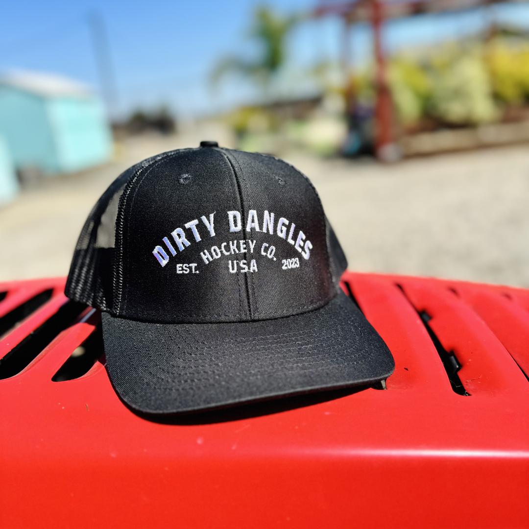 a black dirty dangles hockey co mesh snapback trucker hat outside on a red lawn mower.