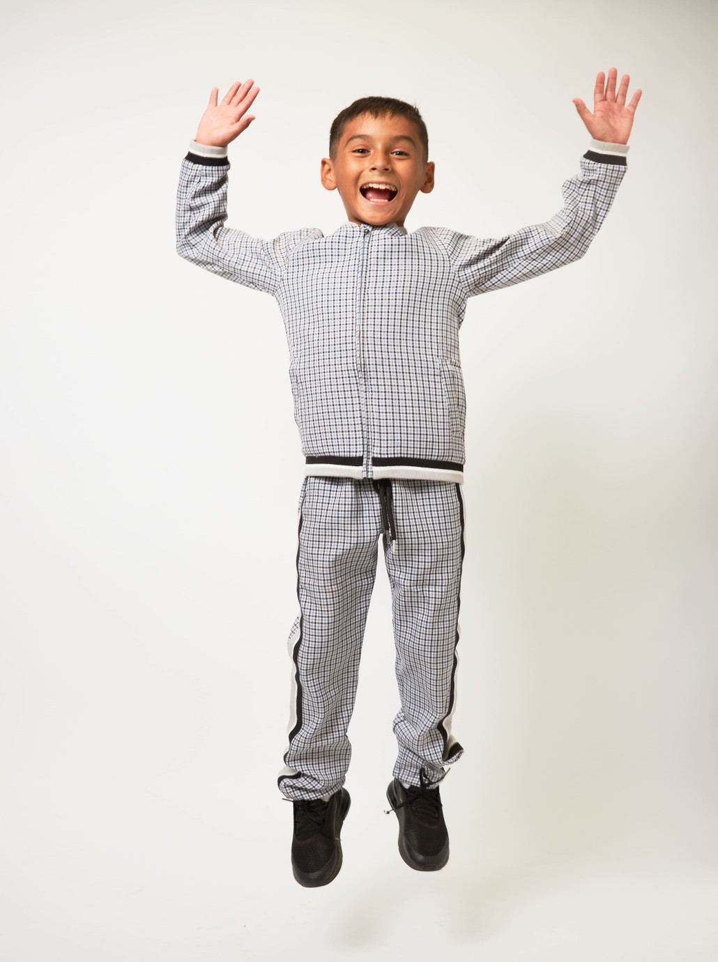 Boy wearing rack suit jumping with arms raised