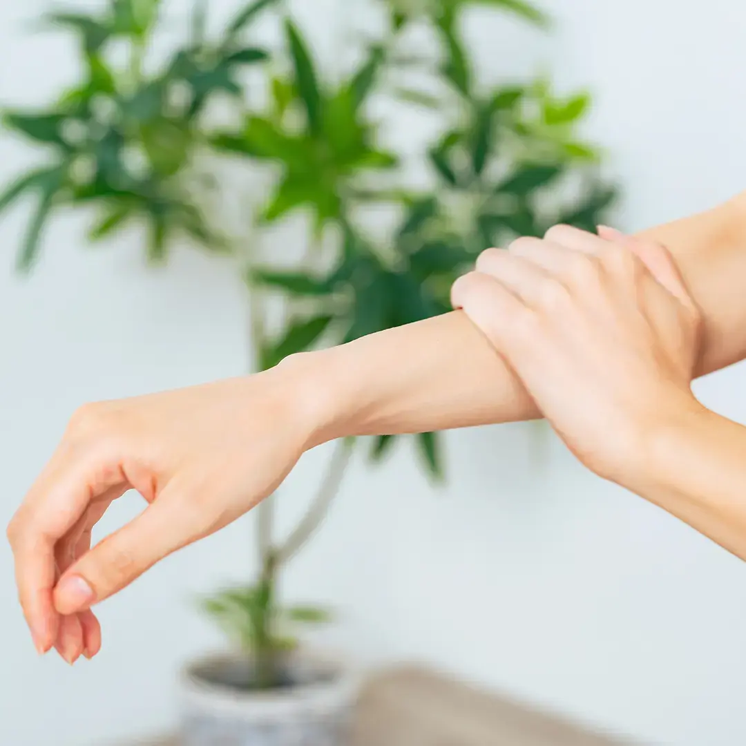 An aesthetic composition of a woman massaging her hands surrounded by floral artwork