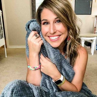 picture of a smiling woman holding a gray blanket