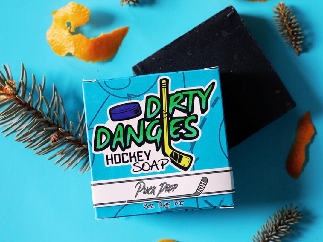 puck drop charcoal pine orange peel and vanilla soap bar on a blue background