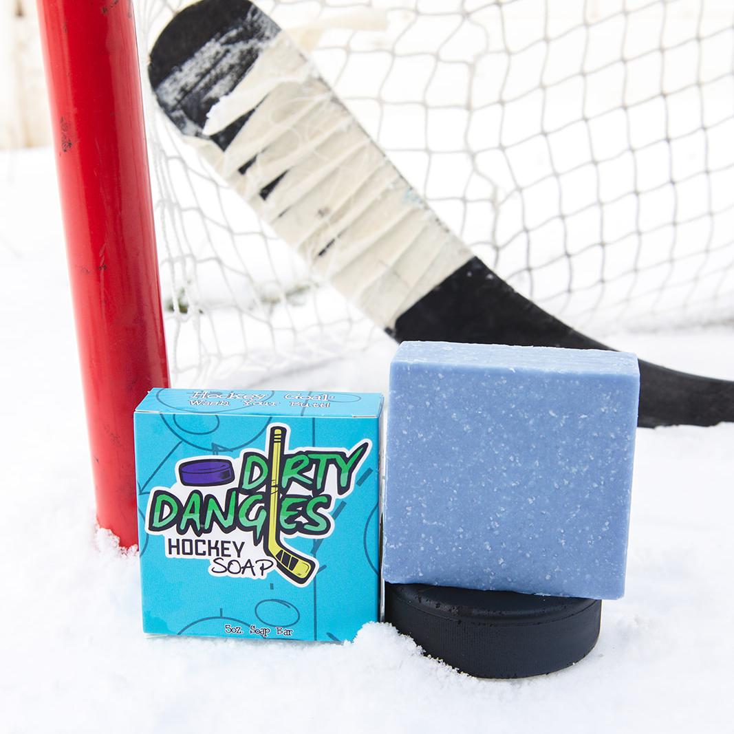 the michigan sea salt hockey soap bar sits in the snow with a hockey goal, hockey puck and a hockey stick.