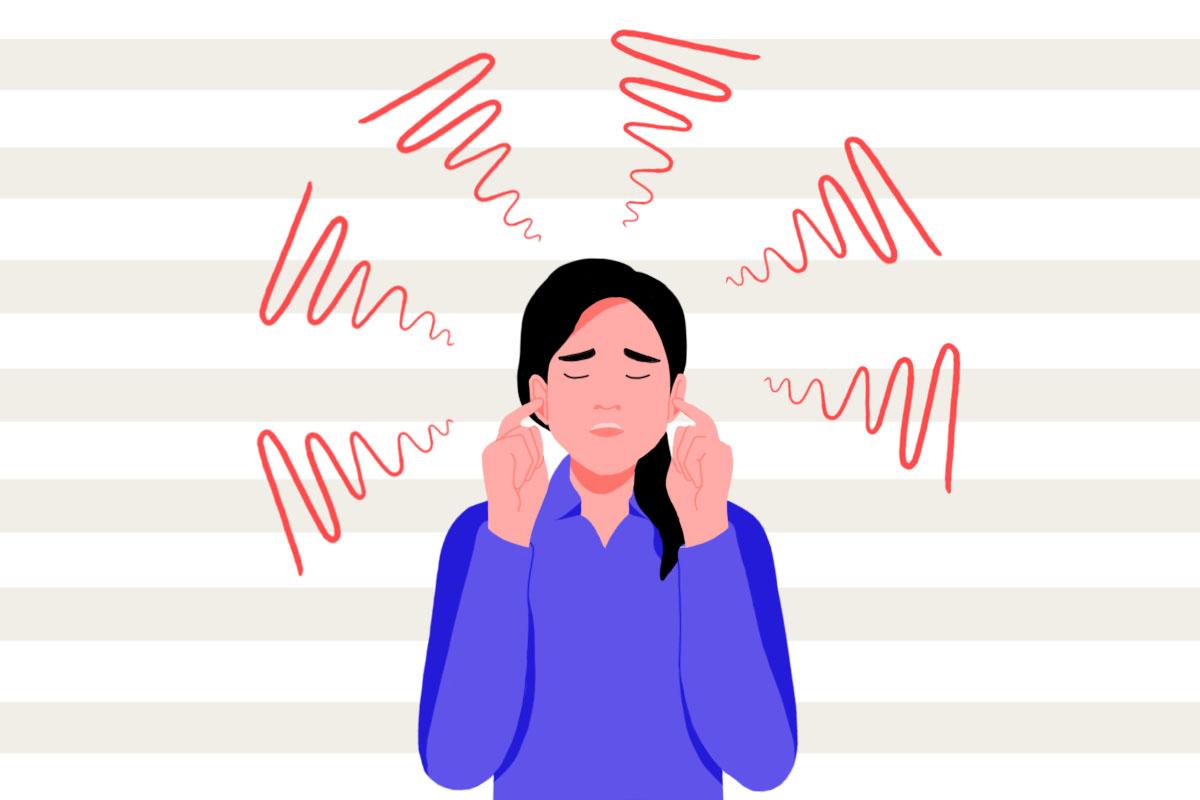 A woman holding her fingers to her ears to block the sound of tinnitus ringing.