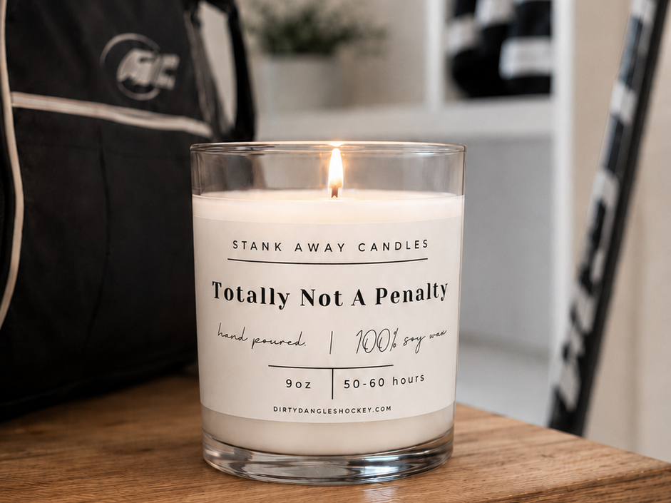 A white scented hockey candle on a wooden bench with hockey gear. Totally not a penalty