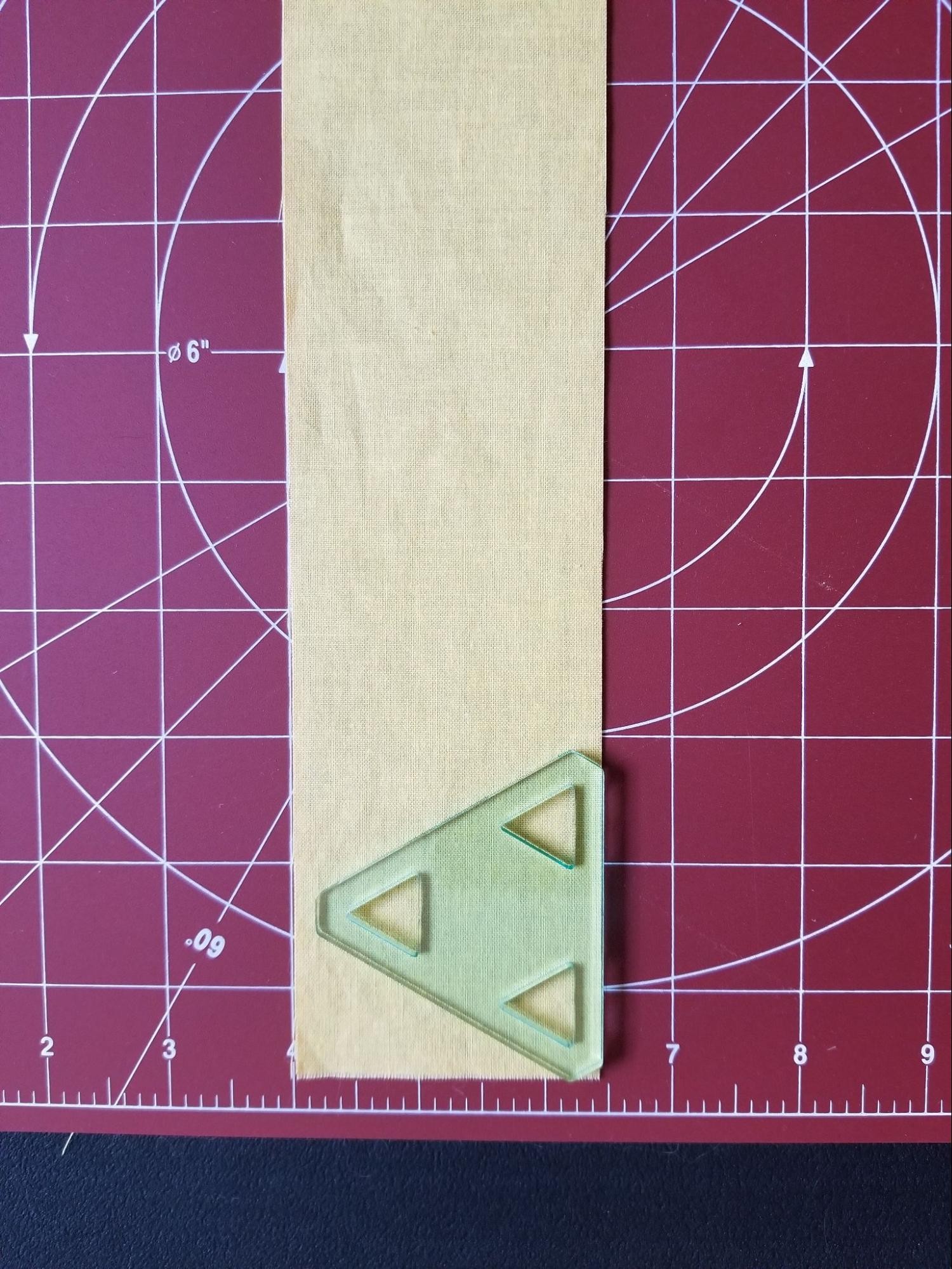 Aligning 60 degree triangle template on fabric strip.