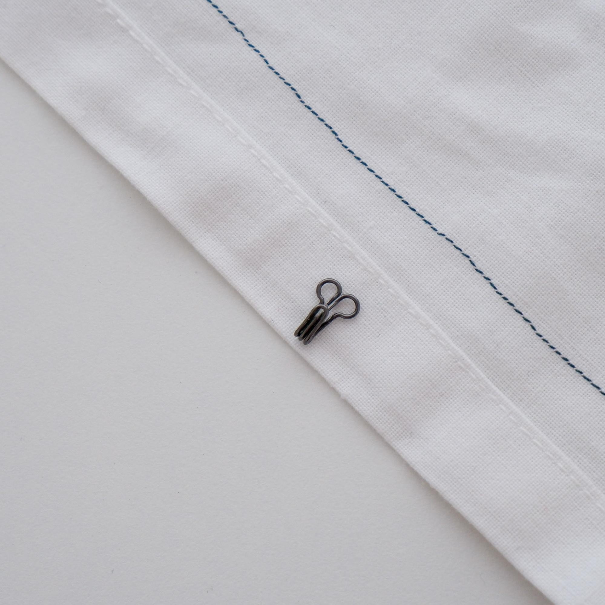 Garment with wrong side facing up and the placement of the hook about ⅛” from edge