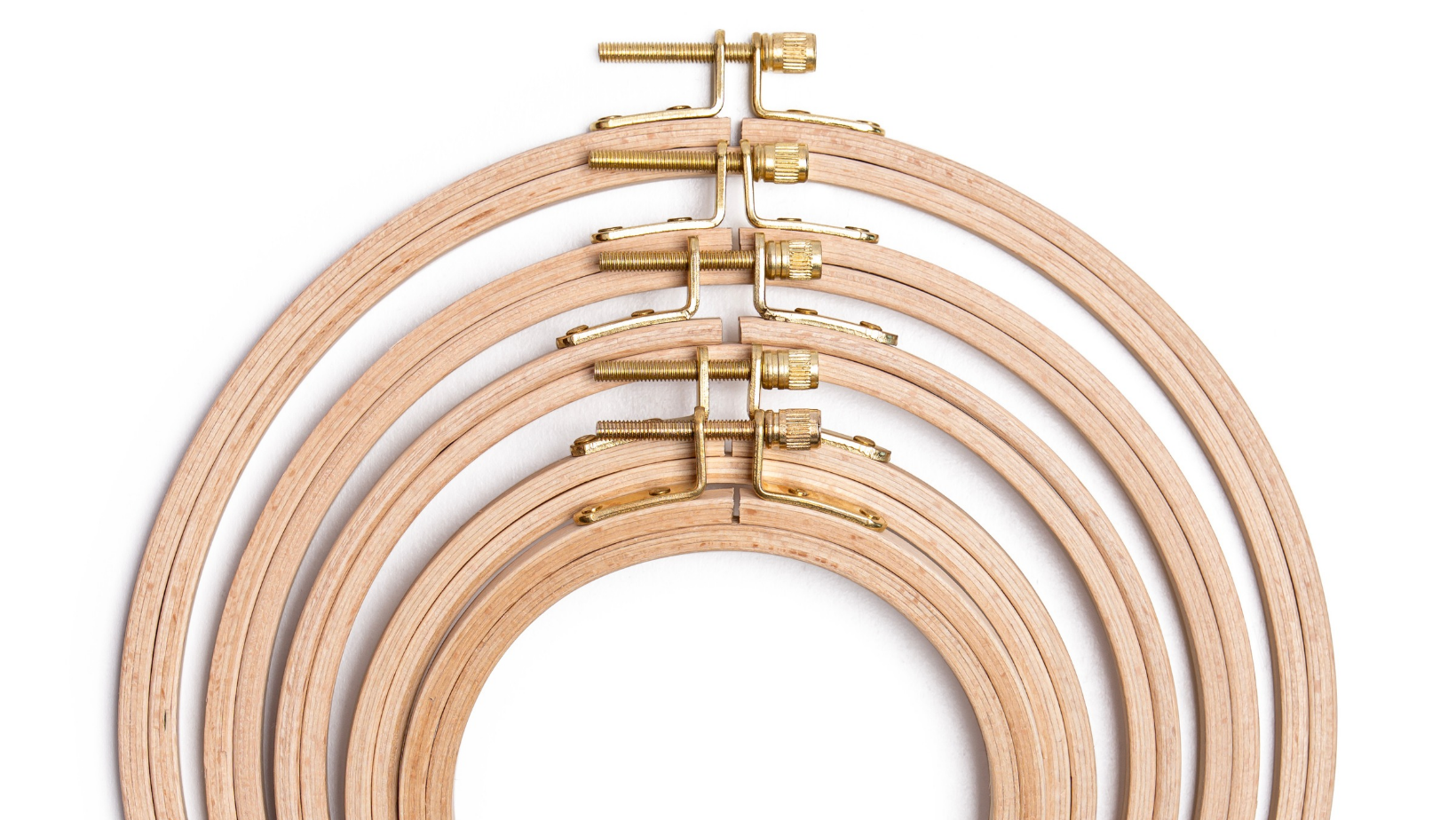 Five wooden embroidery hoops in graduating sizes, nested inside each other with brass fittings.
