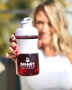 The smart Pressed Juice bottle filled with red juice held by a woman wearing white.