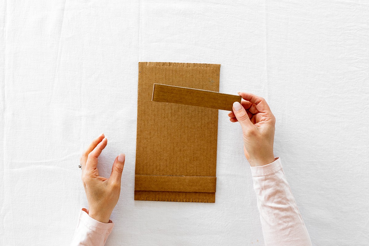 A hand holds a cardboard strut above the rectangle card.