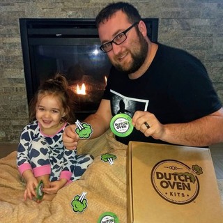 picture of a smiling dad and kid showing their dutch oven kit