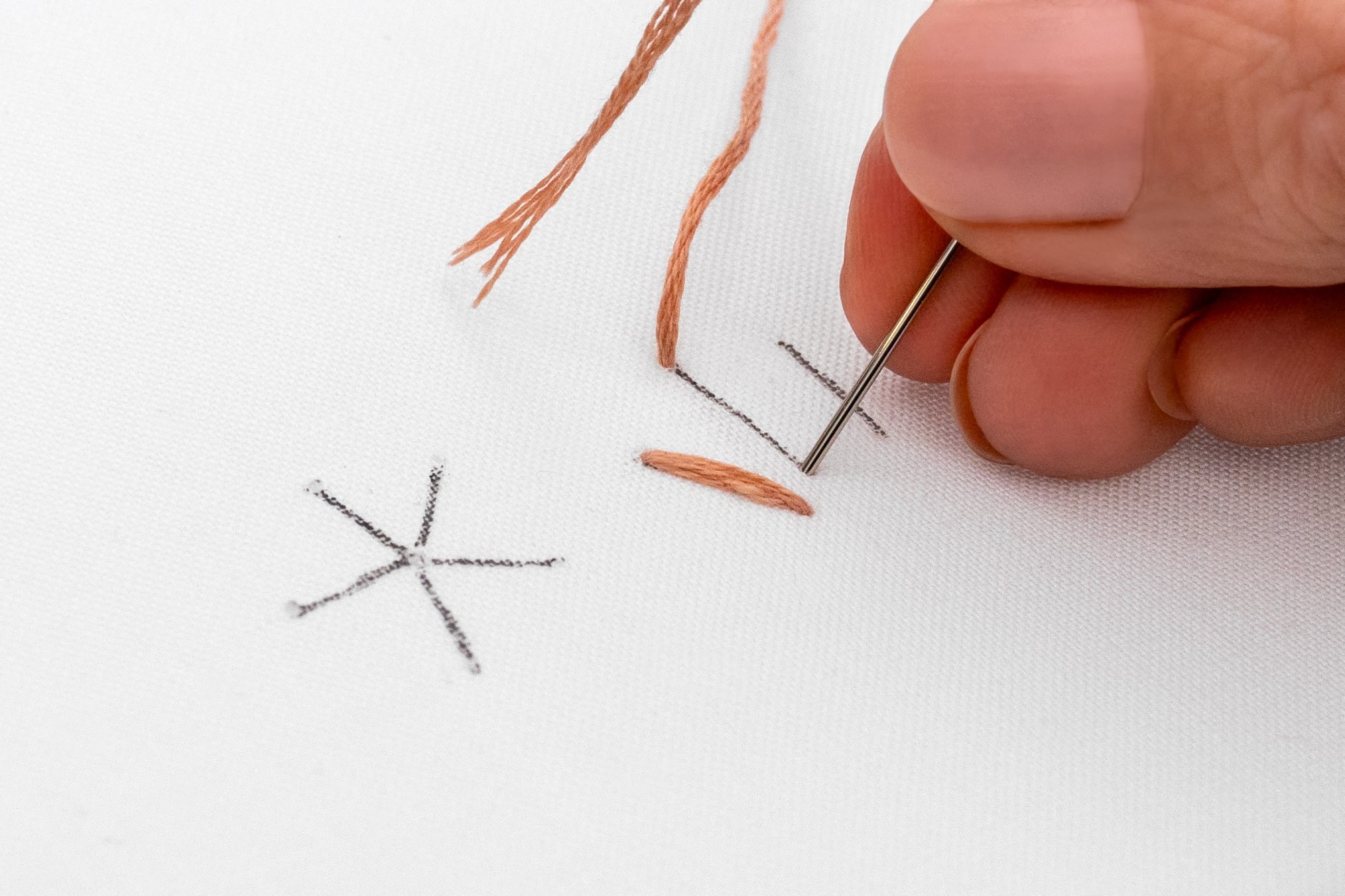 A needle pokes down at the end of a second stitch.