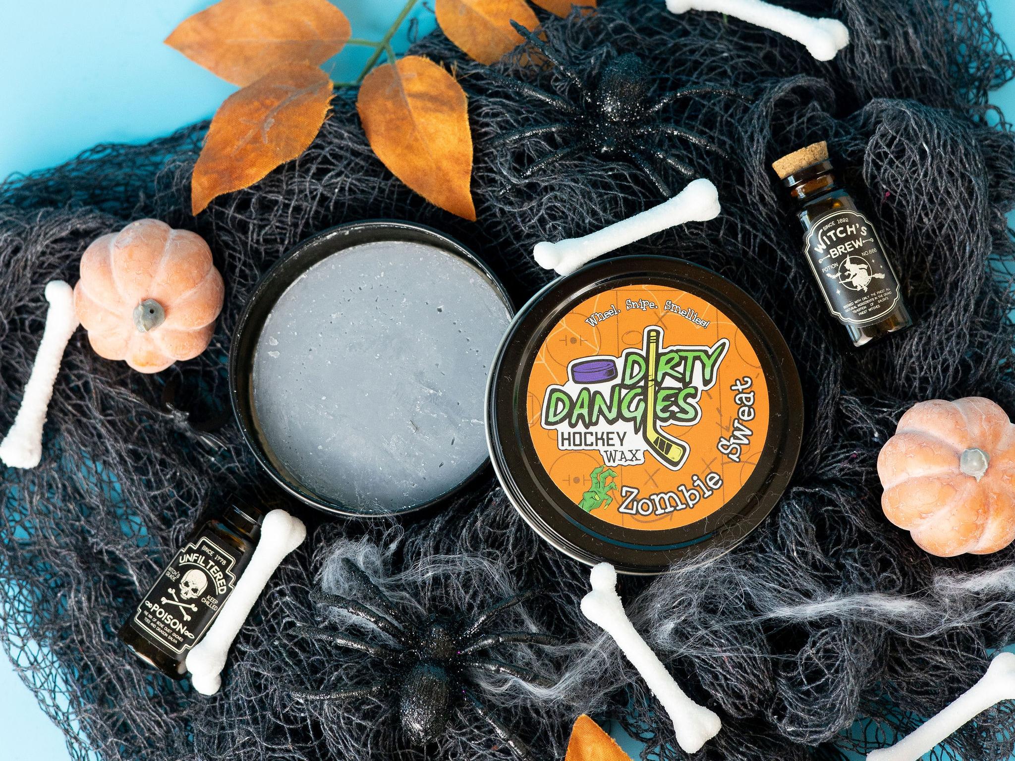 A tin of Halloween dirty dangles hockey zombie sweat pumpkin spice stick wax on a spooky background with spiders, bones and pumpkins