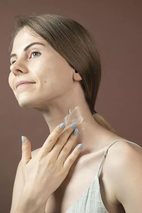 Image of a woman applying cerabuild cream to her neck