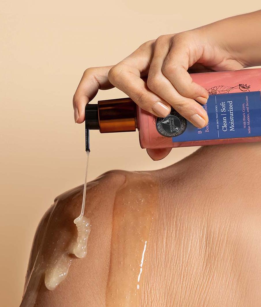 1. The image shows a woman hand holding a Blavana cleanser bottle. She is gently squeezing the bottle, causing a clear liquid to come out of the bottle. The background is a neutral, beige color.