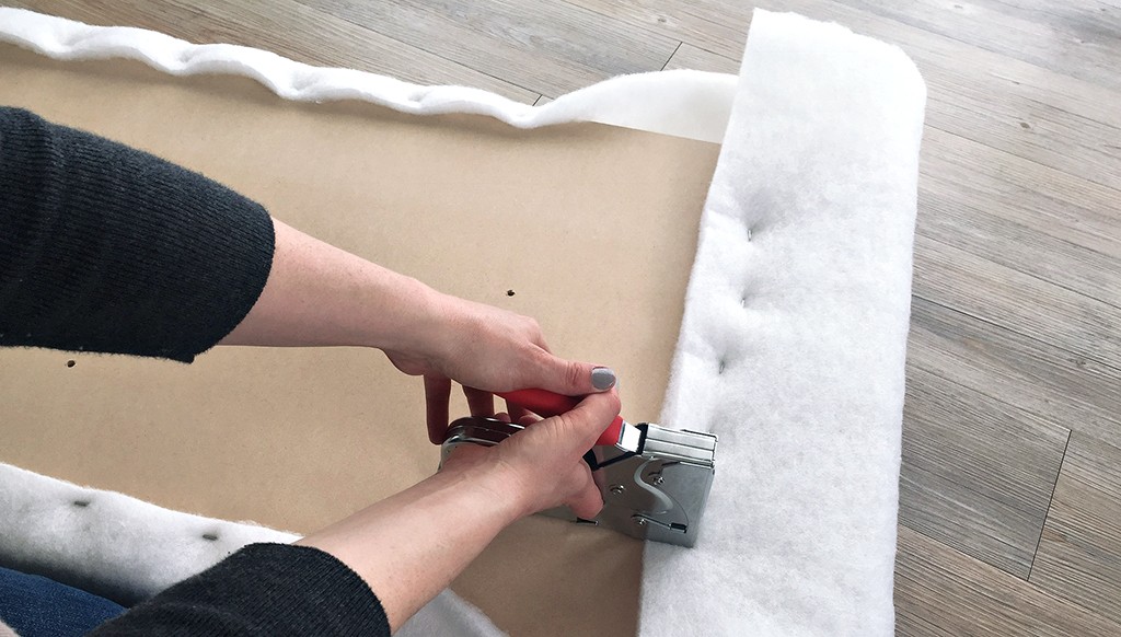 A hand staples foam onto a board.