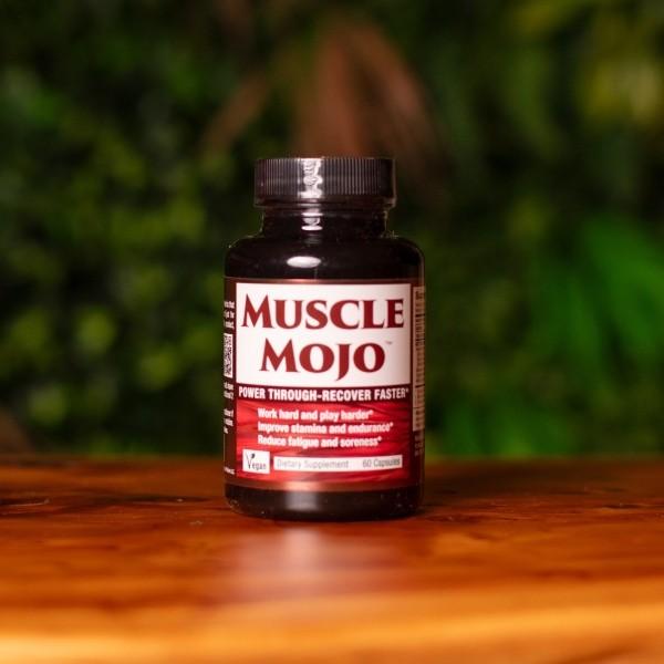 A bottle of Muscle Mojo on a wooden shelf with greenery in the background