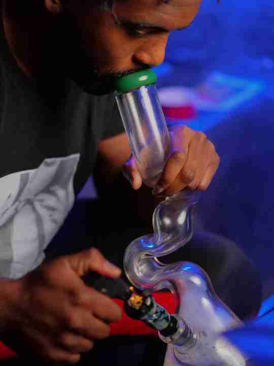 man in smoking from a glass dab rig