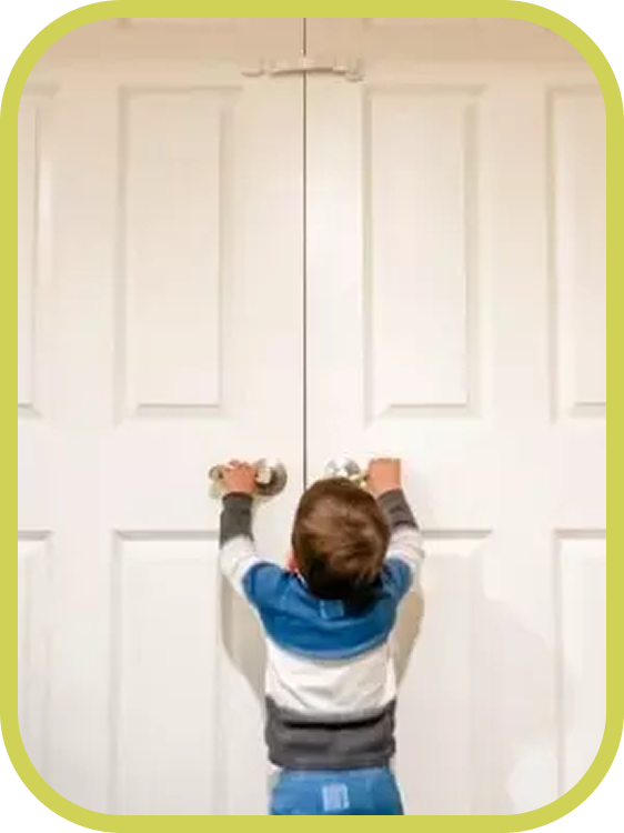 A toddler reaches up trying to open closed double doors. The image highlights the challenge of keeping curious children out of certain rooms without using bulky gates.