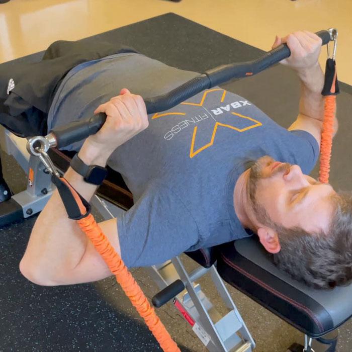 man using xbar resistance system for chest presses