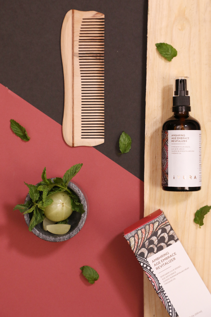 iYURA Ambhring with its beautiful Madhubani painting packaging and a wooden comb. Also shown is Gooseberry