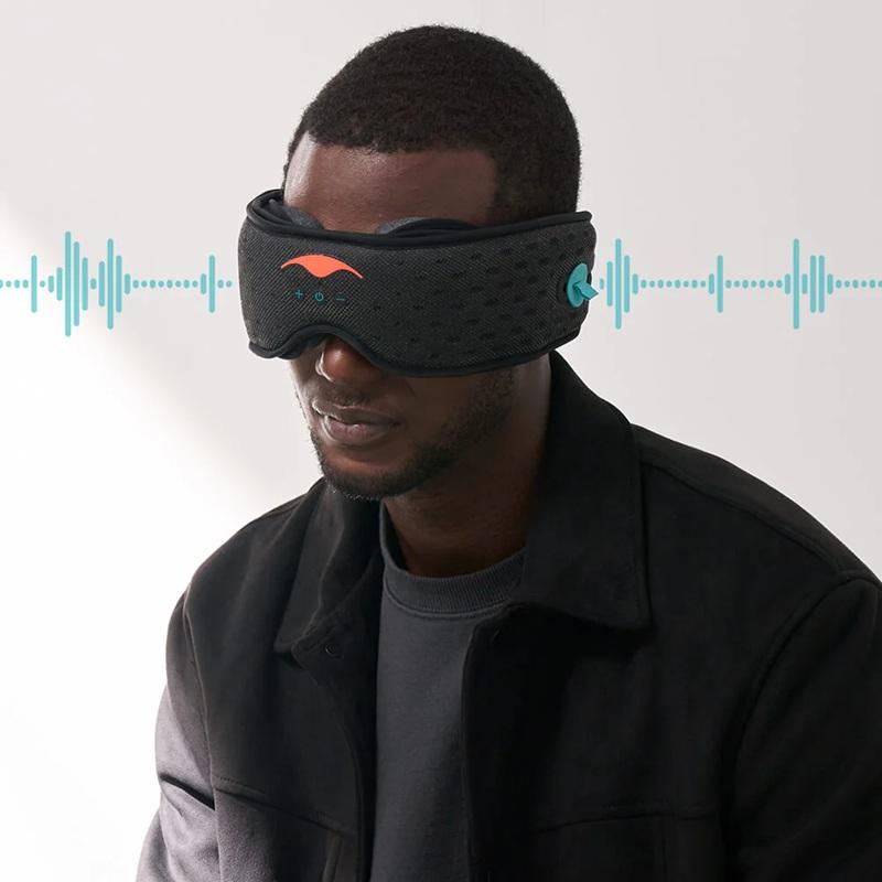 A man wearing a black mesh Bluetooth sleep mask with blue sound waves coming out of the speakers on the side of the mask.
