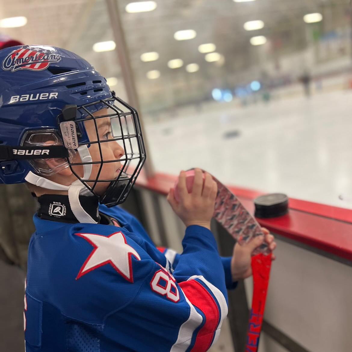 a youth hockey player applying dirty dangles hockey stick wax to a taped blade