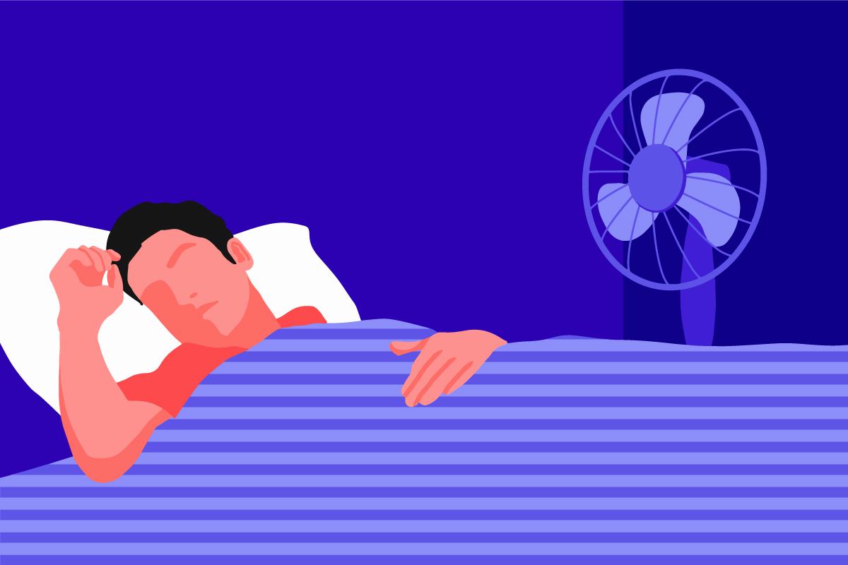 A man lying on a bed, sleeping with a fan.