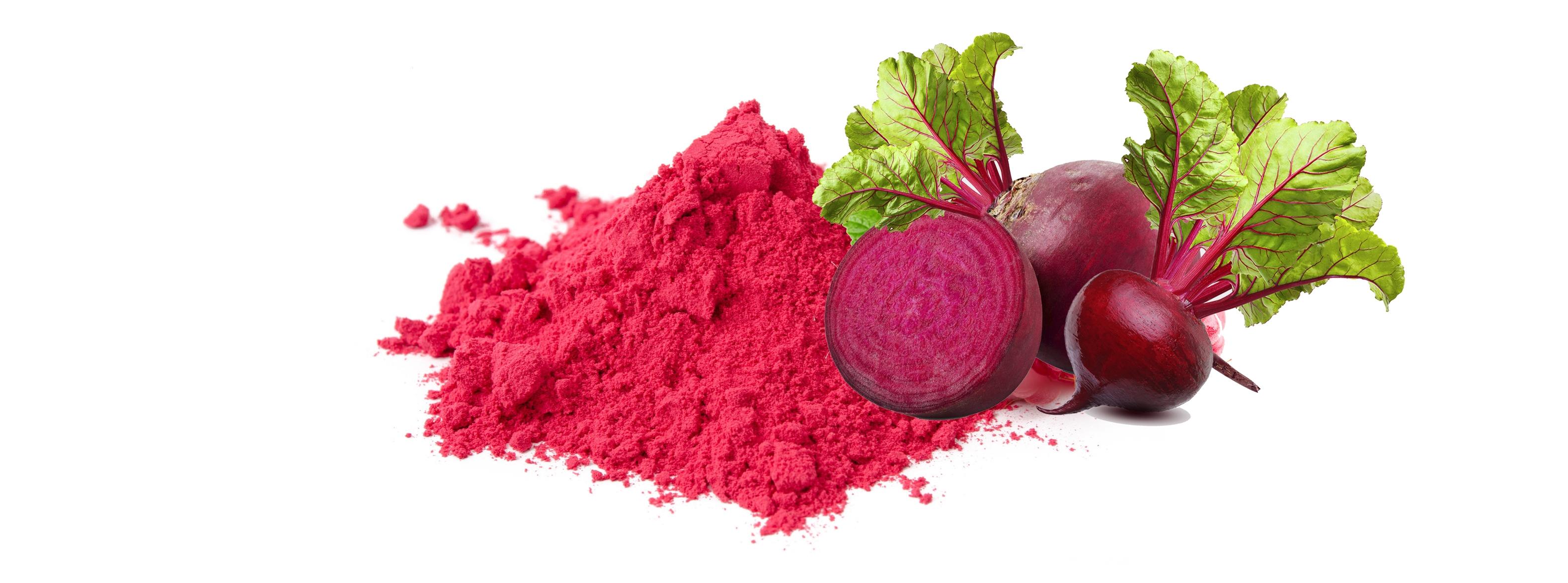 Three raw purple-red colored beets with one cut in half, next to a pile of pink beetroot powder