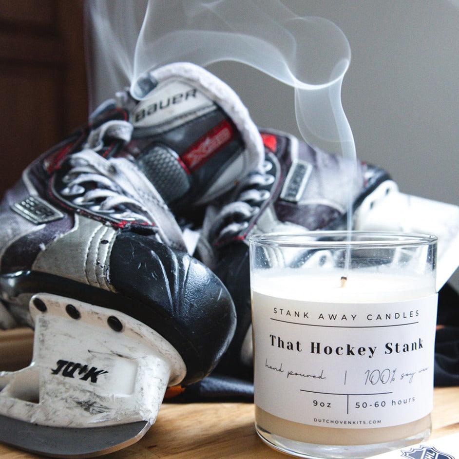 A white candle sits on a table with a pair of ice skates and a hockey stick. That hockey stank.