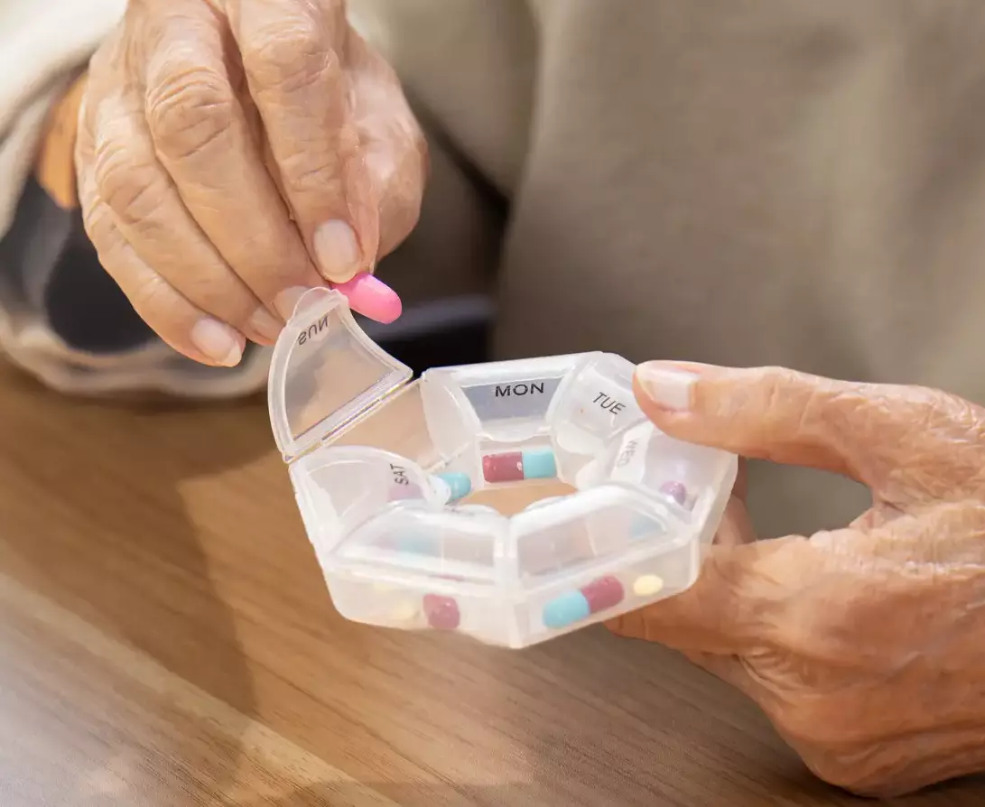 Woman taking her daily medications from the pill box