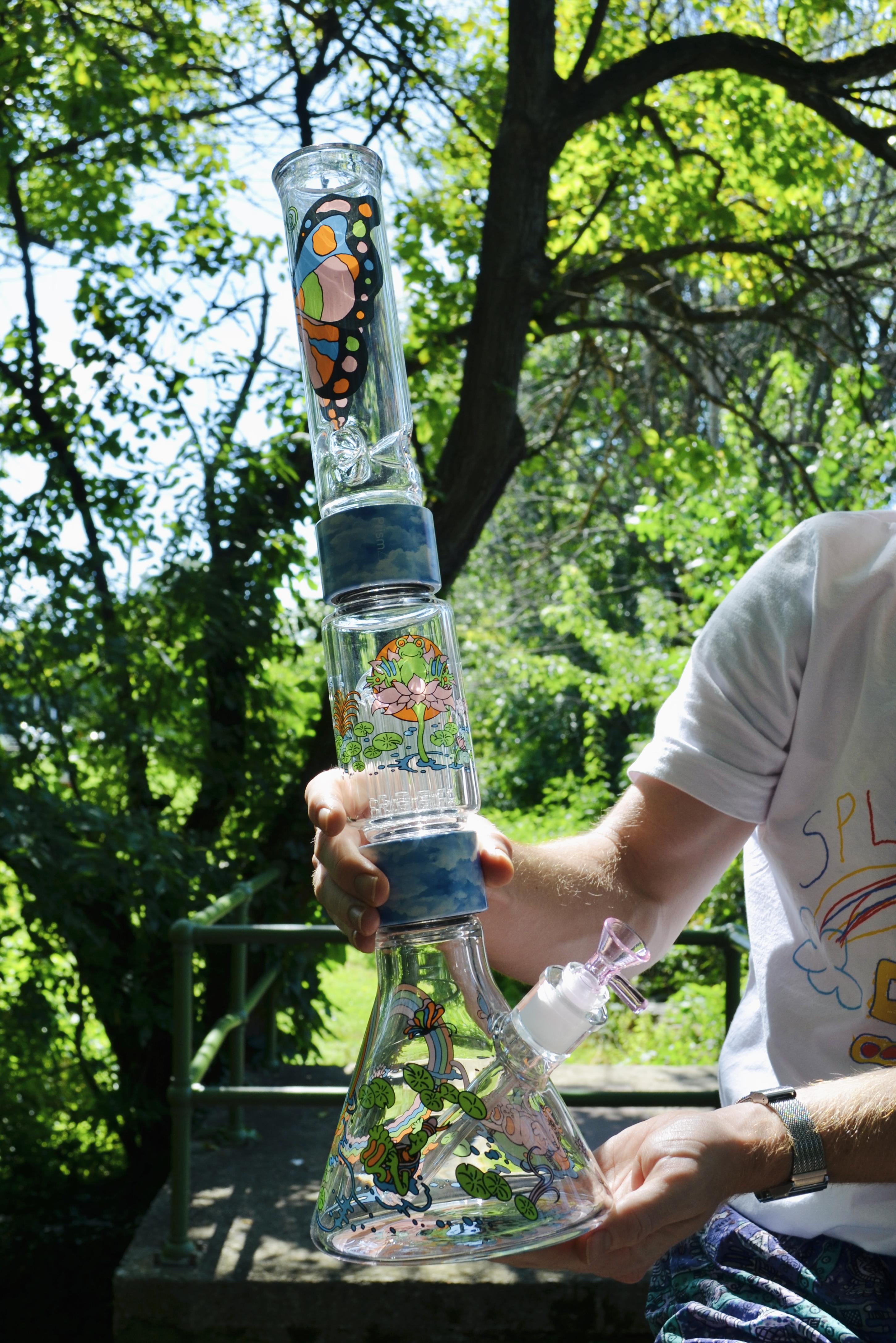 An image of a man holding a tall double stack Prism Bong with the Pond Life decal on its pieces