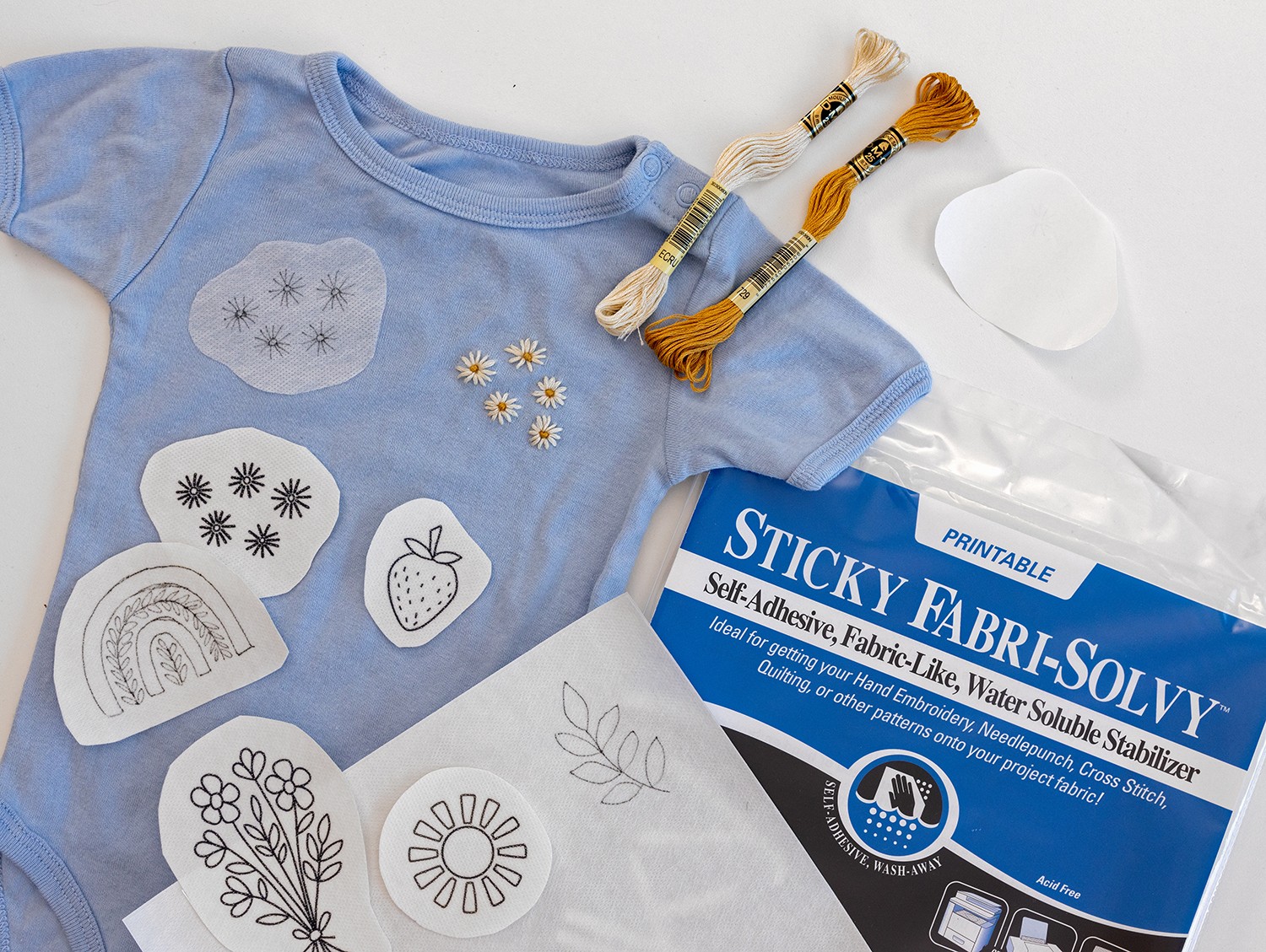 Patches of Sticky Fabri-Solvy with drawn designs lie on a T-shirt.