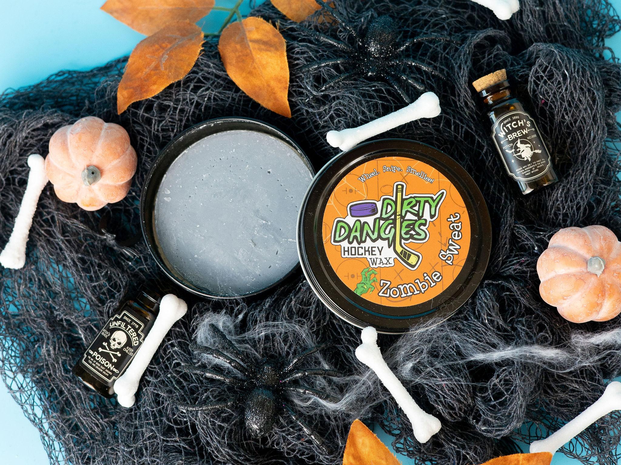 A tin of Halloween dirty dangles hockey zombie sweat pumpkin spice stick wax on a spooky background with spiders, bones and pumpkins