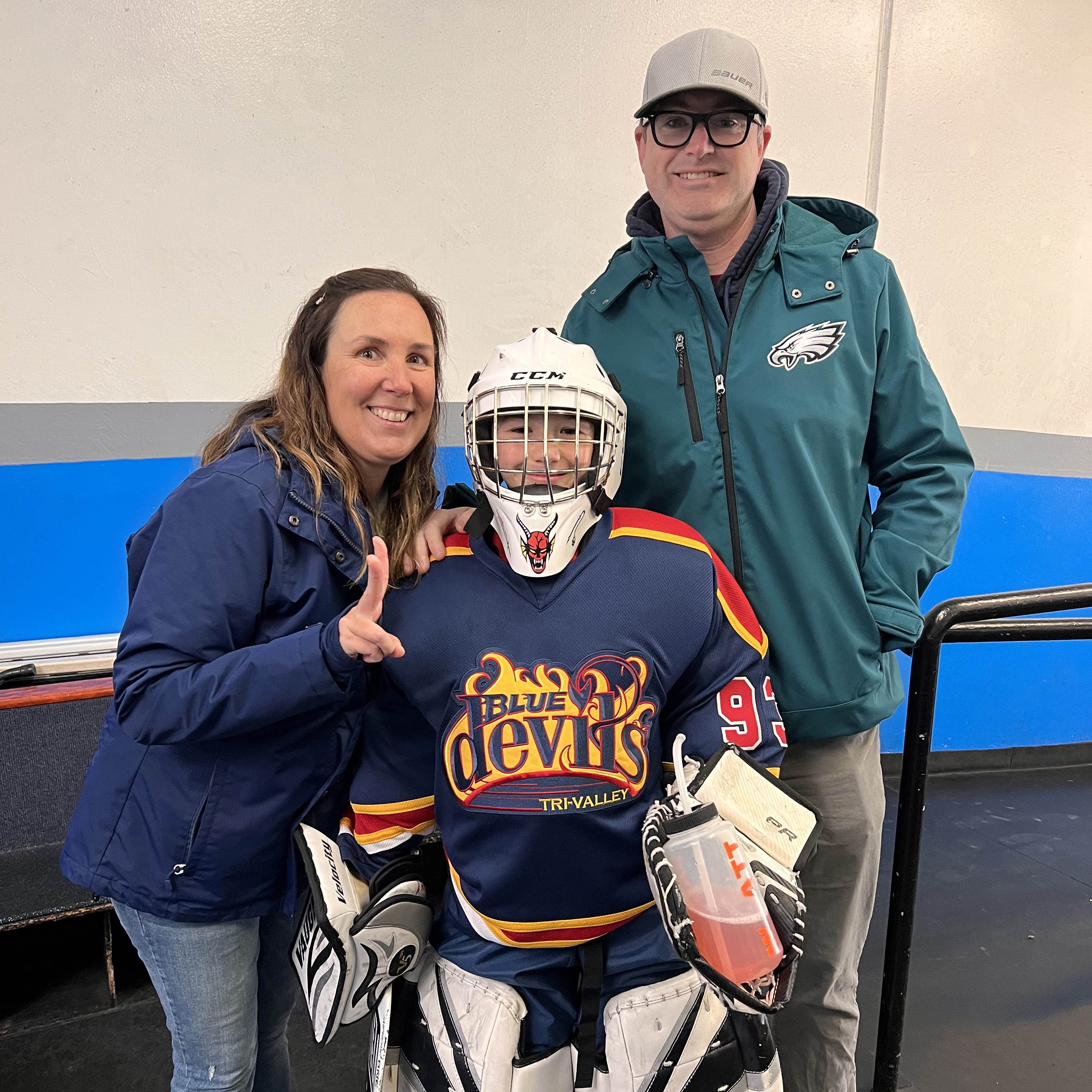 Our hockey family posing with our son who plays goalie