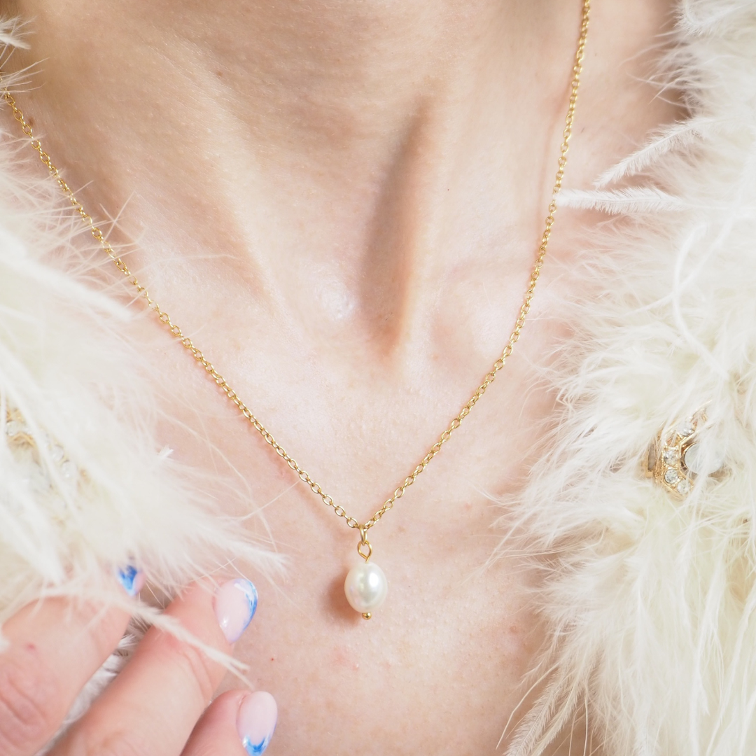 A close-up of a woman wearing a gold necklace with a fur shawl on.