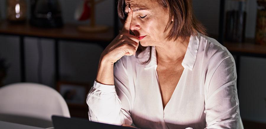 Tired mature woman looking away from her laptop screen