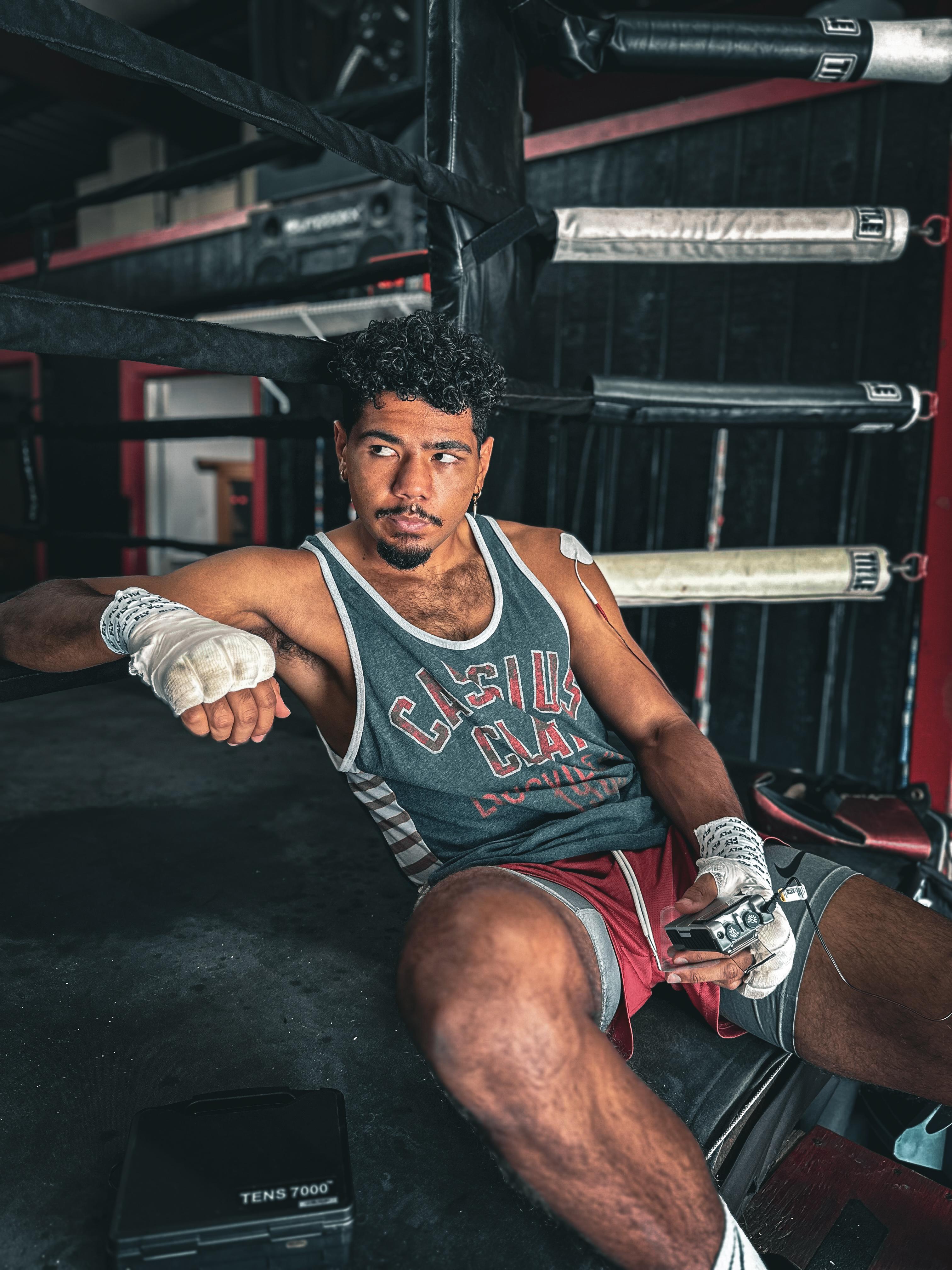 Darius Fulghum using a TENS 7000 device while sitting on boxing ring.