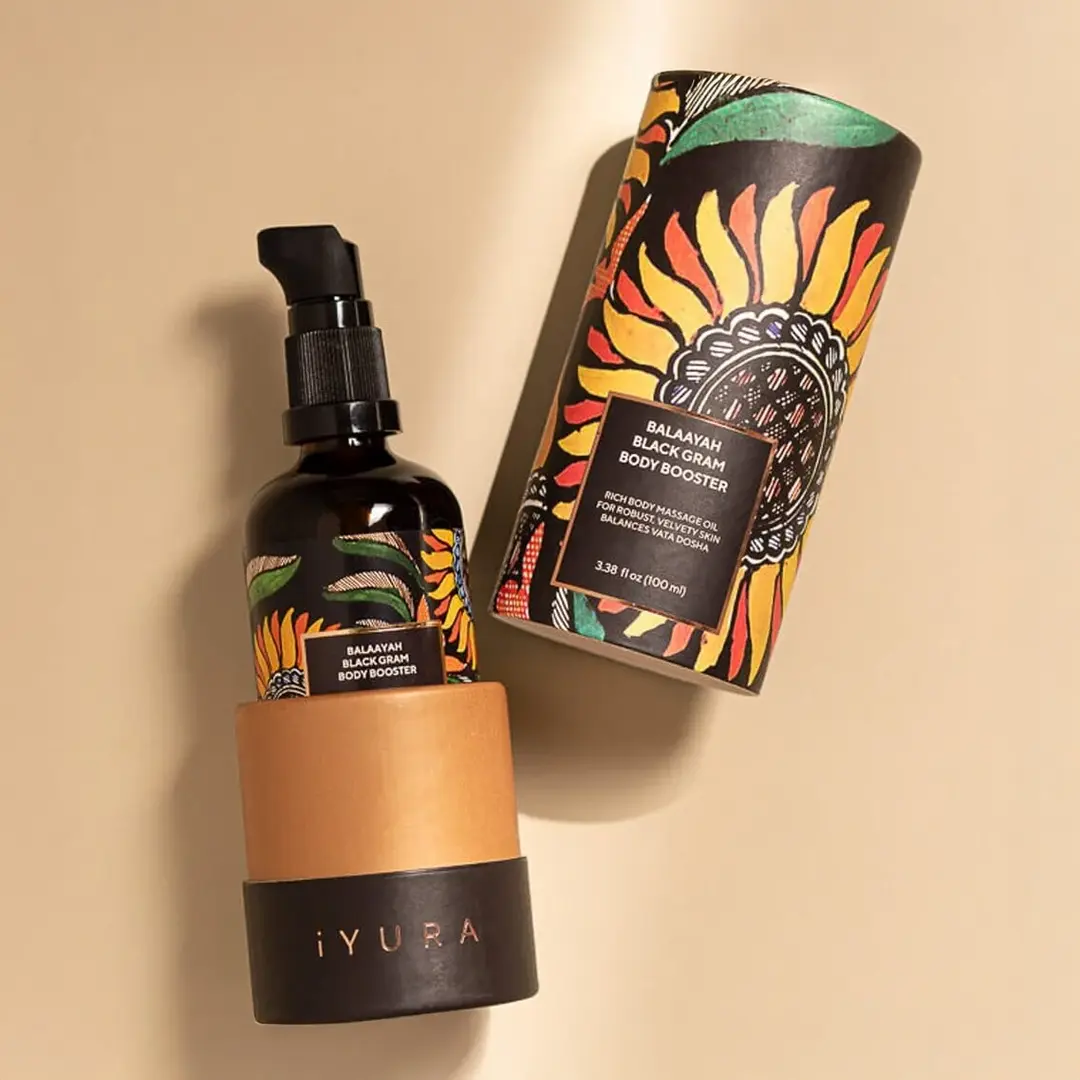 A bottle of Yauvari amplified youth spring surrounded by ingredients like black gram, cut in half limes, neroli flowers with it's buds and leaves.