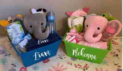 A boy and a girl customized gift basket filled with a pink or gray elephant, and baby accessories