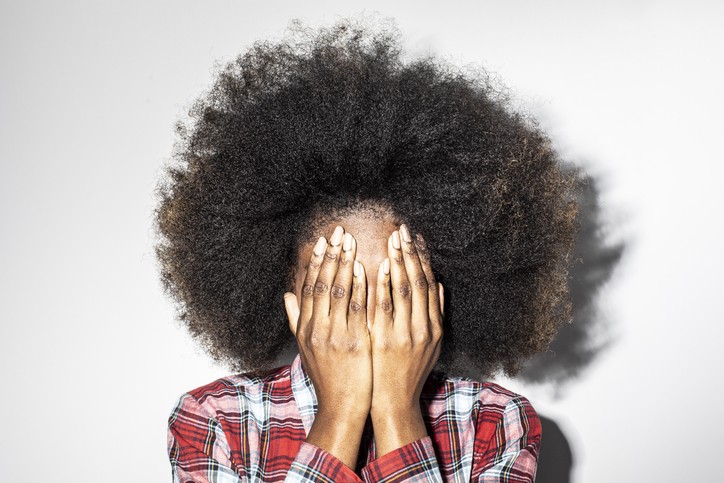 Black woman with afro and hands in her face