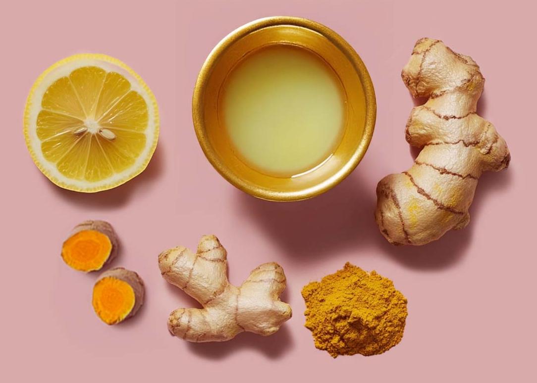 The image shows a collection of natural ingredients like lemon juice in a copper bowl, ginger, turmeric and a lemon slice.