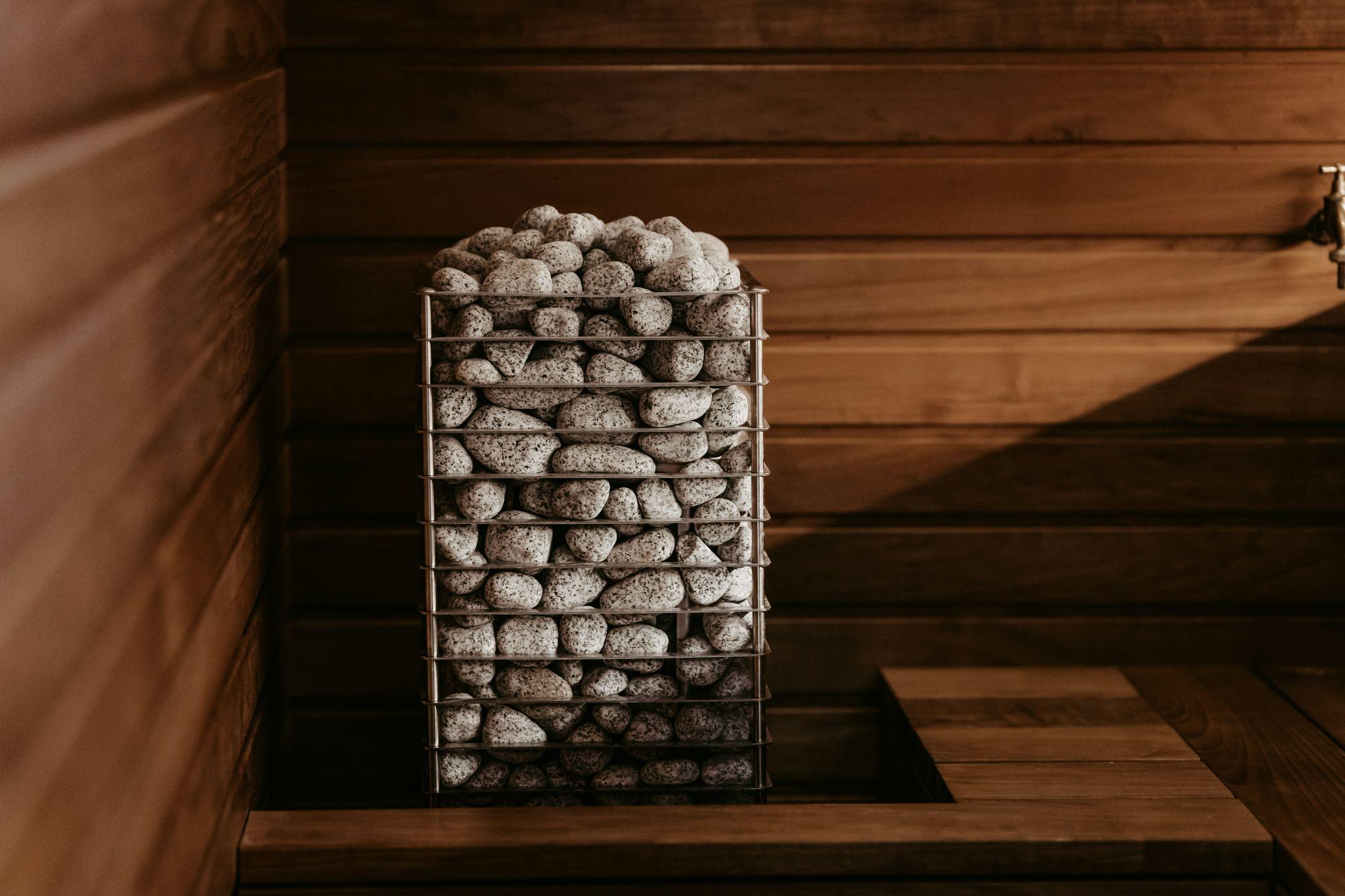 Sauna heater filled with sauna stones inside a wood-paneled sauna