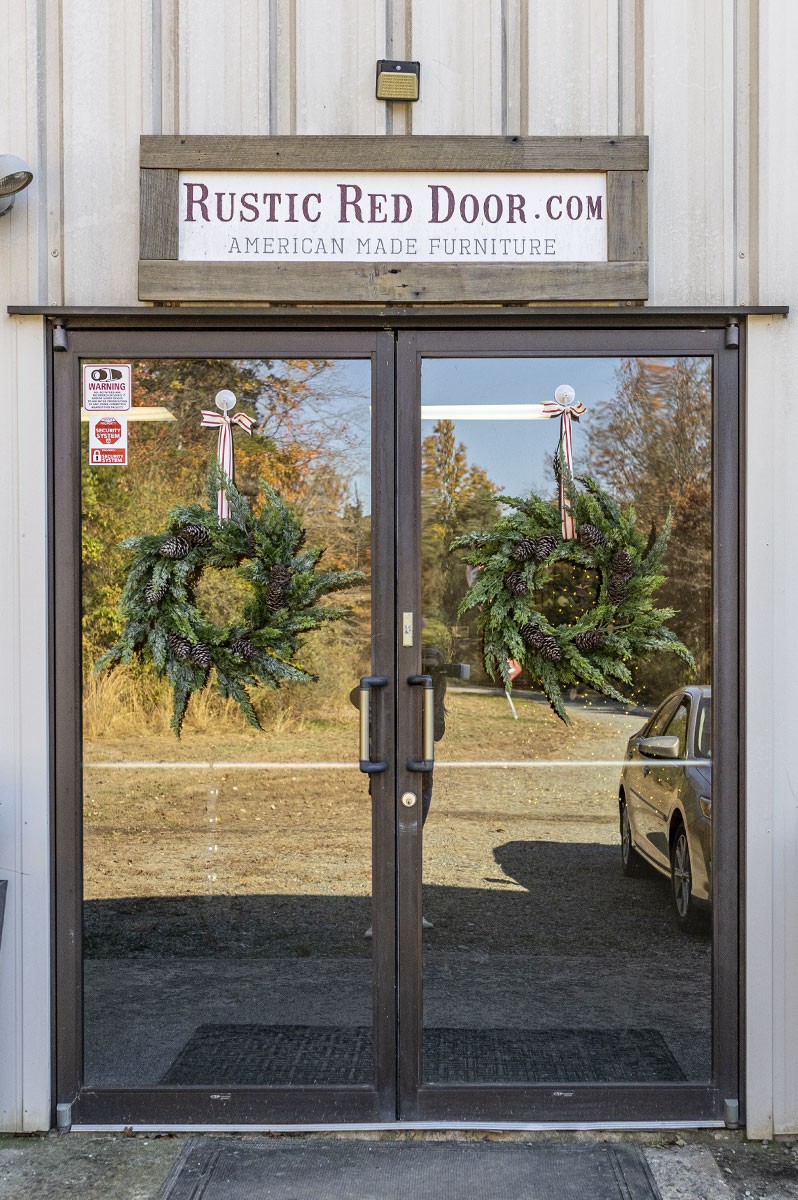 decorated front door wreath at rustic red door