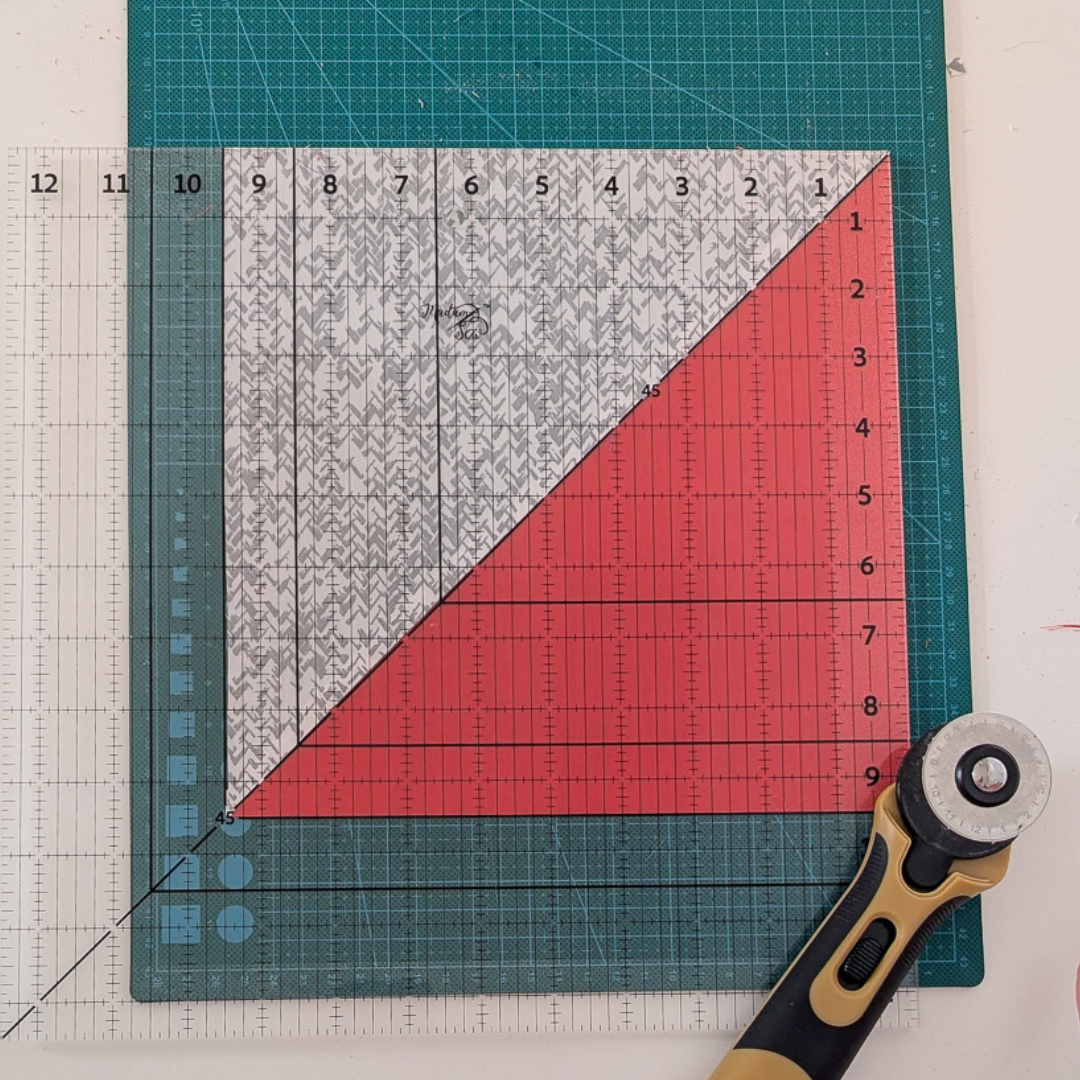 Picture of a HST with the 45 degree line lined up on the block’s 45 degree line and the bottom and left edges of the block lined up on the horizontal and vertical 9.5” bold lines of the Madam Sew 12.5” Square-Up Quilting Ruler.