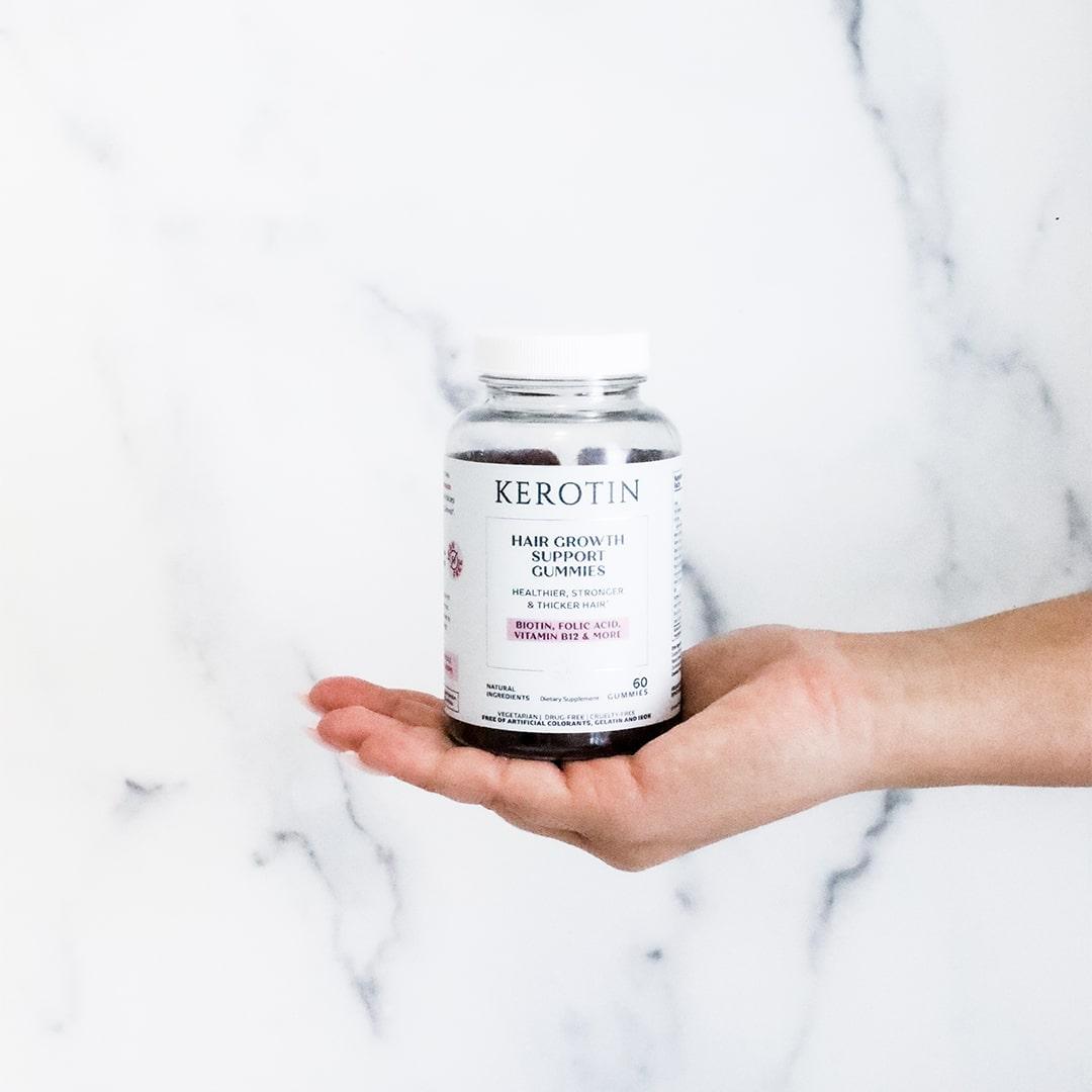 model picking a gummy from inside a bottle of Kerotin Hair Vitamin Gummies